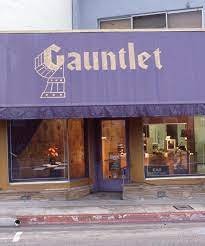 Fachada de la tienda Gauntlet con su Iconico toldo morado y letras doradas, especializada en modificaciones corporales.