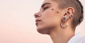 Mujer mostrando múltiples piercings con materiales como titanio, acero quirúrgico, oro, plata y madera.
